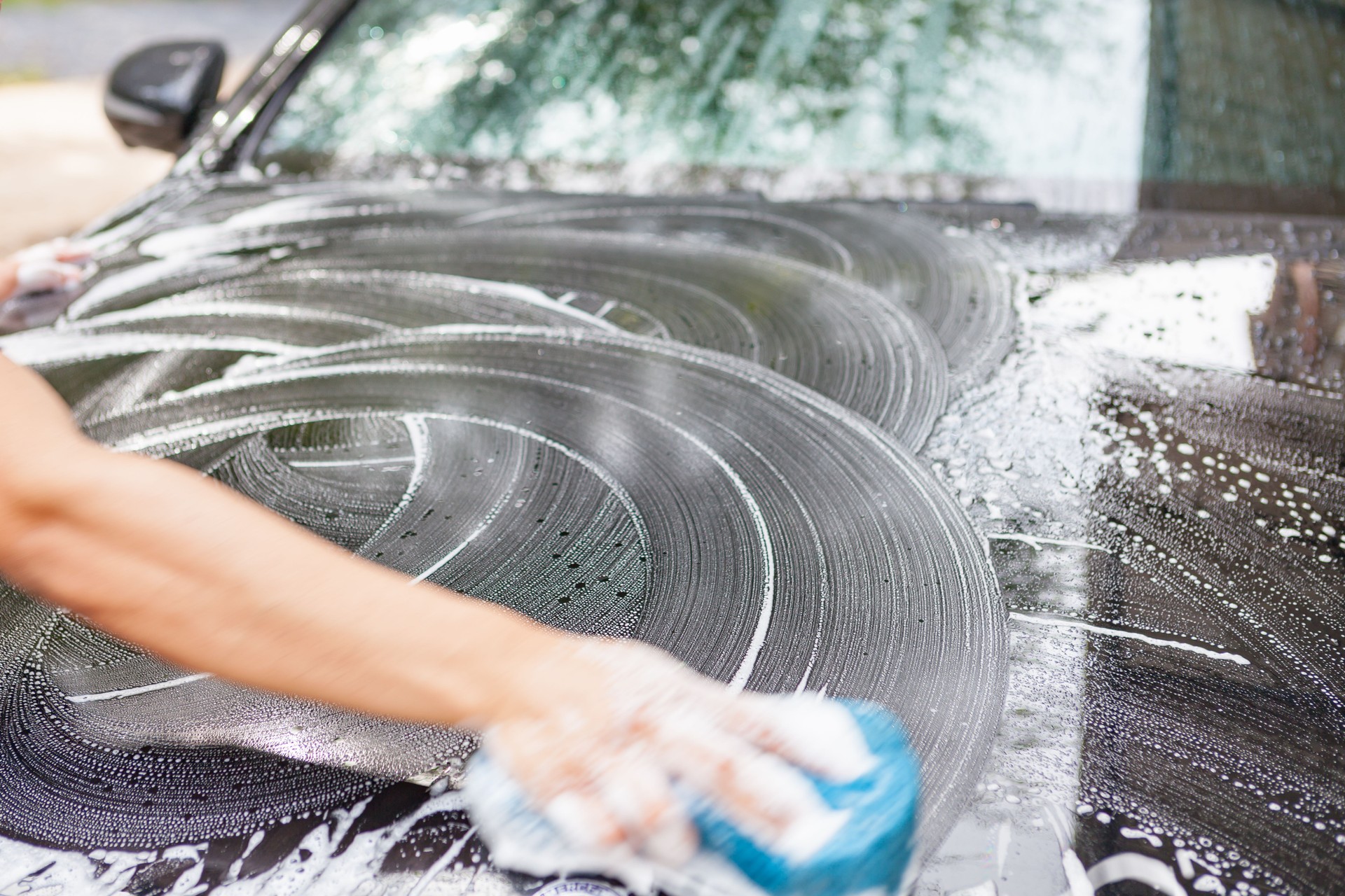Closeup of hand cleaning black car.